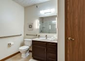 Thumbnail 30 of 32 - A bathroom with a toilet, sink, and mirror.
