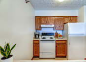 Thumbnail 31 of 32 - A kitchen with white appliances and wooden cabinets.