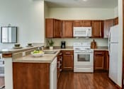 Thumbnail 20 of 22 - A kitchen with wooden cabinets and white appliances.