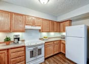 Thumbnail 27 of 28 - A kitchen with wooden cabinets and a white refrigerator.