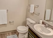 Thumbnail 21 of 25 - A bathroom with a toilet, sink, and towel racks.