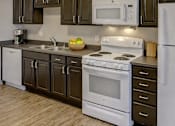 Thumbnail 23 of 25 - A kitchen with white appliances and brown cabinets.