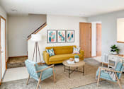 Thumbnail 26 of 28 - A living room with a yellow couch and blue chairs.