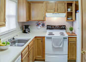 Thumbnail 17 of 17 - A kitchen with wooden cabinets and a white stove top oven.