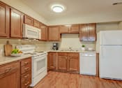 Thumbnail 31 of 32 - A kitchen with wooden cabinets and white appliances.
