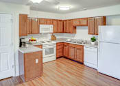 Thumbnail 27 of 28 - A kitchen with wooden cabinets and white appliances.