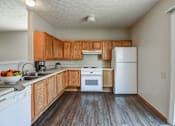 Thumbnail 25 of 27 - A kitchen with wooden cabinets and white appliances.