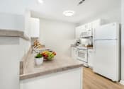 Thumbnail 24 of 26 - A kitchen with a white refrigerator and a countertop with a bowl of fruit on it.