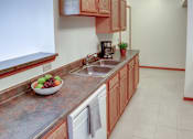 Thumbnail 28 of 29 - A kitchen with wooden cabinets and a marble countertop.