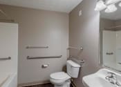 Thumbnail 44 of 83 - A white toilet sits in a bathroom next to a sink and a shower.