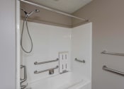 Thumbnail 47 of 83 - A white shower stall with a silver shower head and grab bars.