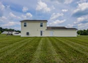Thumbnail 65 of 83 - A white barn with a brown roof sits in a grassy field.