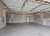 Thumbnail 35 of 83 - A spacious garage with a door and walls covered in drywall.