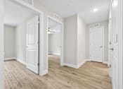 Thumbnail 11 of 31 - A room with white doors and wooden floors.
