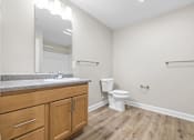 Thumbnail 14 of 31 - A bathroom with a toilet, sink, and wooden floors.