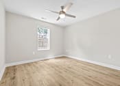 Thumbnail 21 of 31 - A room with a ceiling fan and a window with a white frame.
