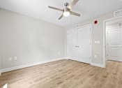 Thumbnail 17 of 31 - A room with a ceiling fan and three doors.