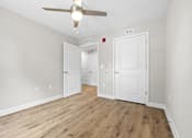 Thumbnail 12 of 31 - A room with a ceiling fan and wooden flooring.