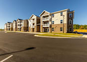 Thumbnail 17 of 55 - A row of apartment buildings with a parking lot in front.