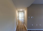 Thumbnail 27 of 55 - A long hallway with wooden floors and white walls.