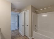 Thumbnail 42 of 55 - A white bathroom with a tub and a door.