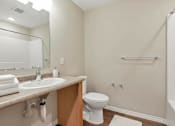 Thumbnail 29 of 31 - A white toilet sits in a bathroom next to a sink and a bathtub.