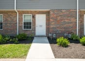 Thumbnail 44 of 72 - a sidewalk in front of a brick house with a white door