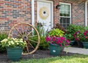 Thumbnail 55 of 72 - a front yard with pots of flowers and a wagon wheel