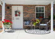 Thumbnail 65 of 72 - the front porch of a brick house with two wicker chairs and a white door