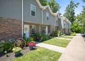 Thumbnail 49 of 72 - a front yard with flowers and a wagon wheel in front of a house
