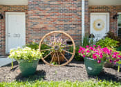 Thumbnail 48 of 72 - a yard with flowers and a wagon wheel in front of a building