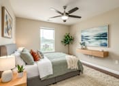 Thumbnail 43 of 45 - A bedroom with a bed, a ceiling fan, and a painting on the wall.