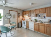 Thumbnail 22 of 24 - A kitchen with a white table and chairs and wooden cabinets.