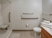 Thumbnail 32 of 32 - A white toilet sits in a bathroom next to a towel bar and a towel rack.