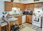 Thumbnail 28 of 28 - A kitchen with wooden cabinets and a white stove top oven.