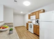 Thumbnail 54 of 57 - A kitchen with a white refrigerator, wooden cabinets, and a bowl of fruit on the counter.
