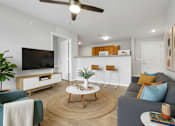 Thumbnail 55 of 57 - A living room with a grey couch, a wooden coffee table, a flat screen TV, and a ceiling fan.