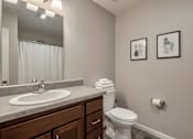Thumbnail 29 of 29 - A bathroom with a toilet, sink, and two pictures on the wall.