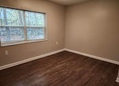 Thumbnail 6 of 30 - A room with a window and wooden flooring.