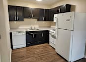 Thumbnail 1 of 30 - A kitchen with black cabinets and a white refrigerator.
