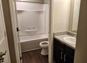 Thumbnail 2 of 30 - A white toilet sits in a small bathroom next to a sink.
