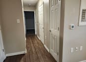 Thumbnail 3 of 30 - A hallway with wood flooring and white doors.