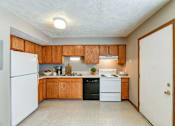 Thumbnail 24 of 27 - A kitchen with wooden cabinets and a white refrigerator.