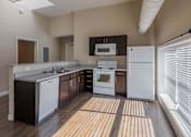 Thumbnail 29 of 39 - A kitchen with white appliances and wooden floors.