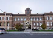 Thumbnail 27 of 39 - A large red brick building with a central arched entrance.