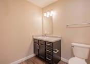 Thumbnail 23 of 39 - A bathroom with a white toilet and a sink with a cabinet underneath it.