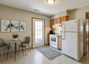Thumbnail 26 of 27 - A kitchen with a white refrigerator, a dining table with two grey chairs, and a rug on the floor.