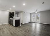 Thumbnail 9 of 38 - an empty living room with a kitchen and a door to a balcony