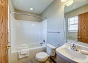 Thumbnail 26 of 28 - A bathroom with a toilet, sink, and bathtub.