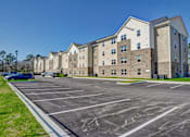 Thumbnail 4 of 35 - A large parking lot in front of a multi-story apartment building.